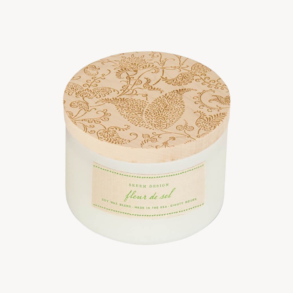 Fleur de Sel combines ocean air and sea salt with top notes of floral and summer fruit. Contains all-natural lavender, lemon and orange oils.  Printing with carved wood blocks is an ancient technique for decorating fabric. These blocks have intricately detailed carvings. These candles are inspired by these print blocks and feature carved maple lids on matte-white, 3-wick vessels, a thoroughly modern interpretation of the originals. Hand poured in the USA with Skeem Designs exclusive soy base.